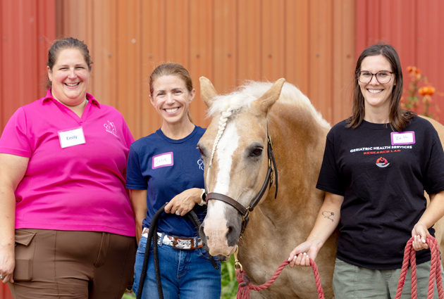 Three women standing with a horse
