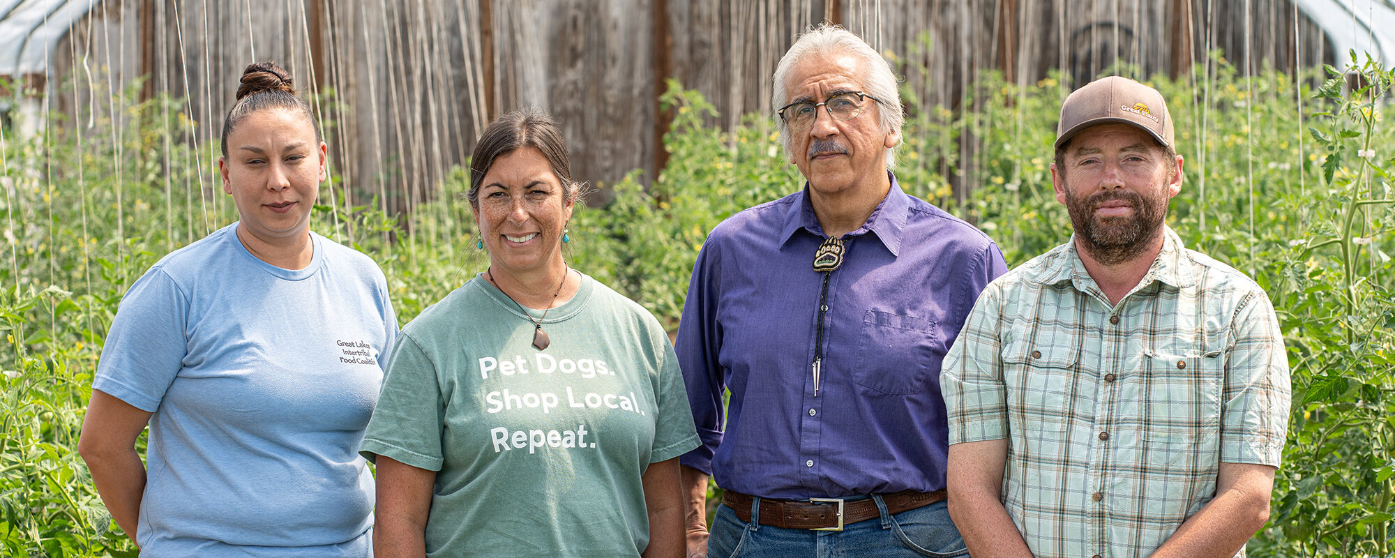 Four people standing together in a greenhouse