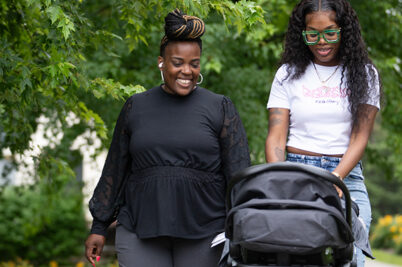 Two women walking outside with a stroller