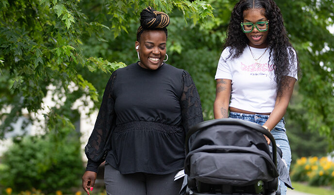 Two women walking outside with a stroller