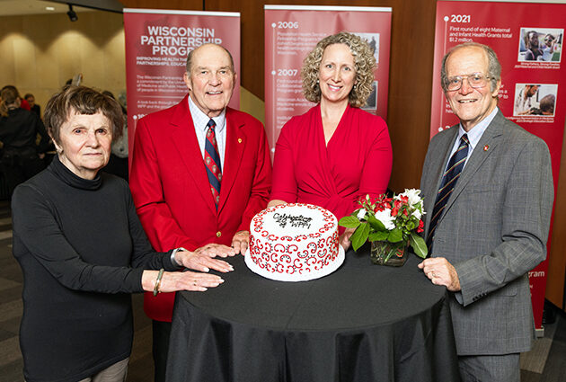 School leaders smile surrounding a celebratory cake