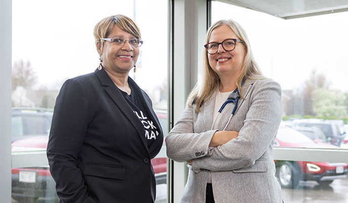 Two women smiling together, one with a stethoscope