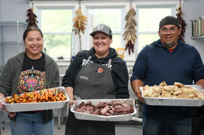 Three individuals standing with trays of food