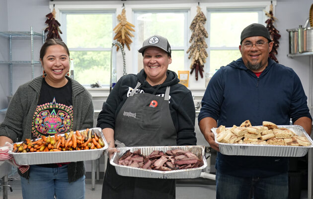 Three individuals standing with trays of food