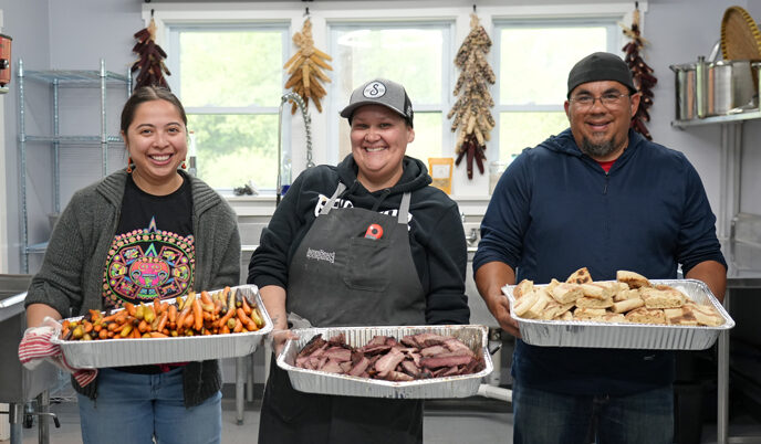 Three individuals standing with trays of food