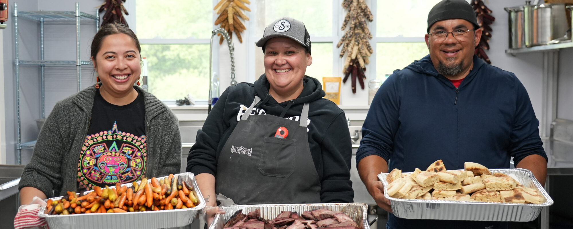 Three individuals standing with trays of food