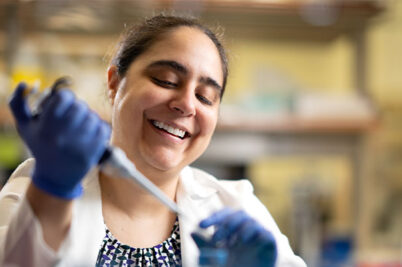 A woman uses a pipette in a lab