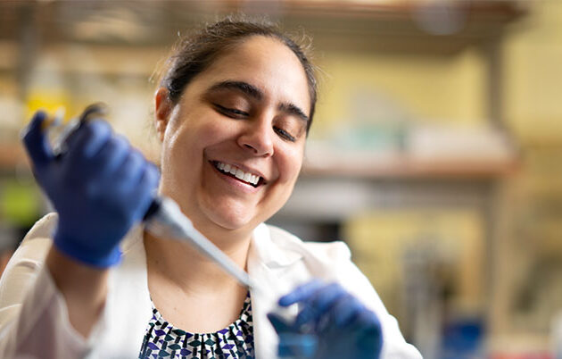 A woman uses a pipette in a lab