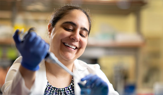 A woman uses a pipette in a lab