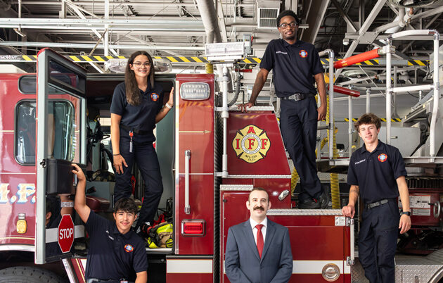 Five people standing on a fire truck