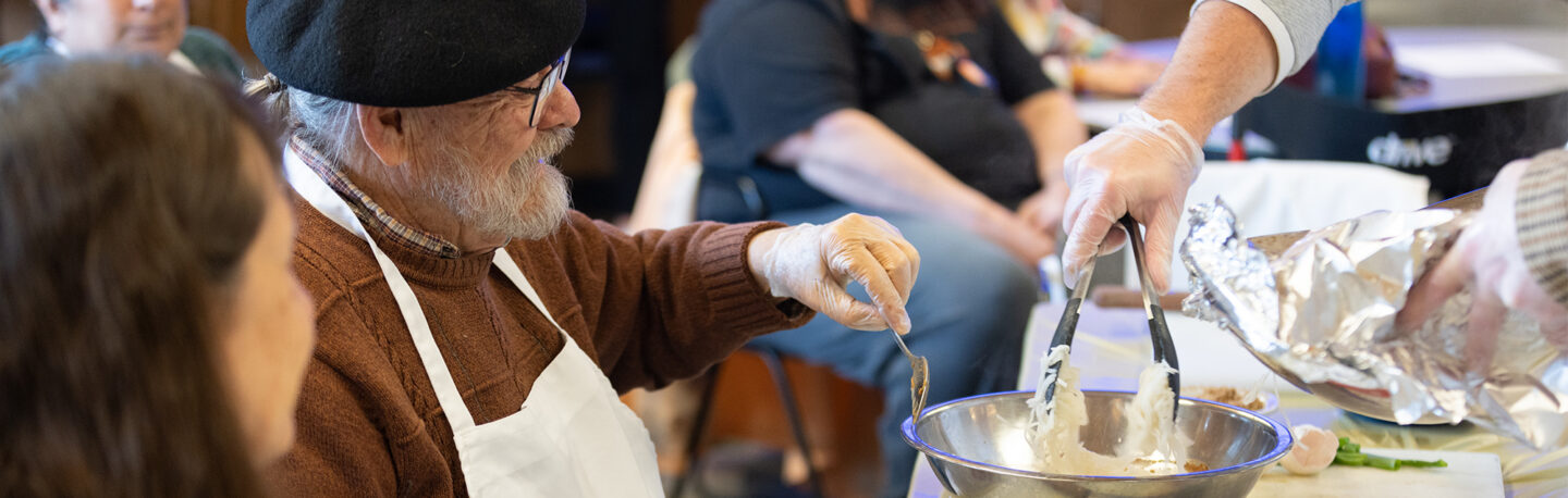 A man grinning while taking a cooking class