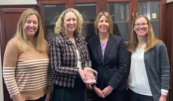 Megan Miller, Amy Kind, Darcy Elzen and Tonya Mathison holding a glass award