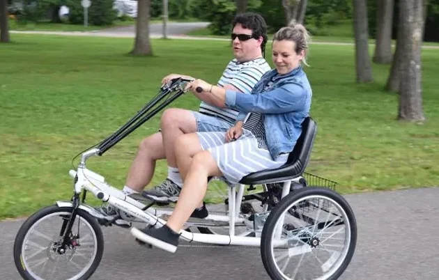 Two people pedaling a three-wheel, two-passenger trike