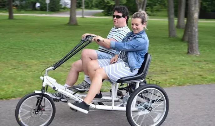 Two people pedaling a three-wheel, two-passenger trike