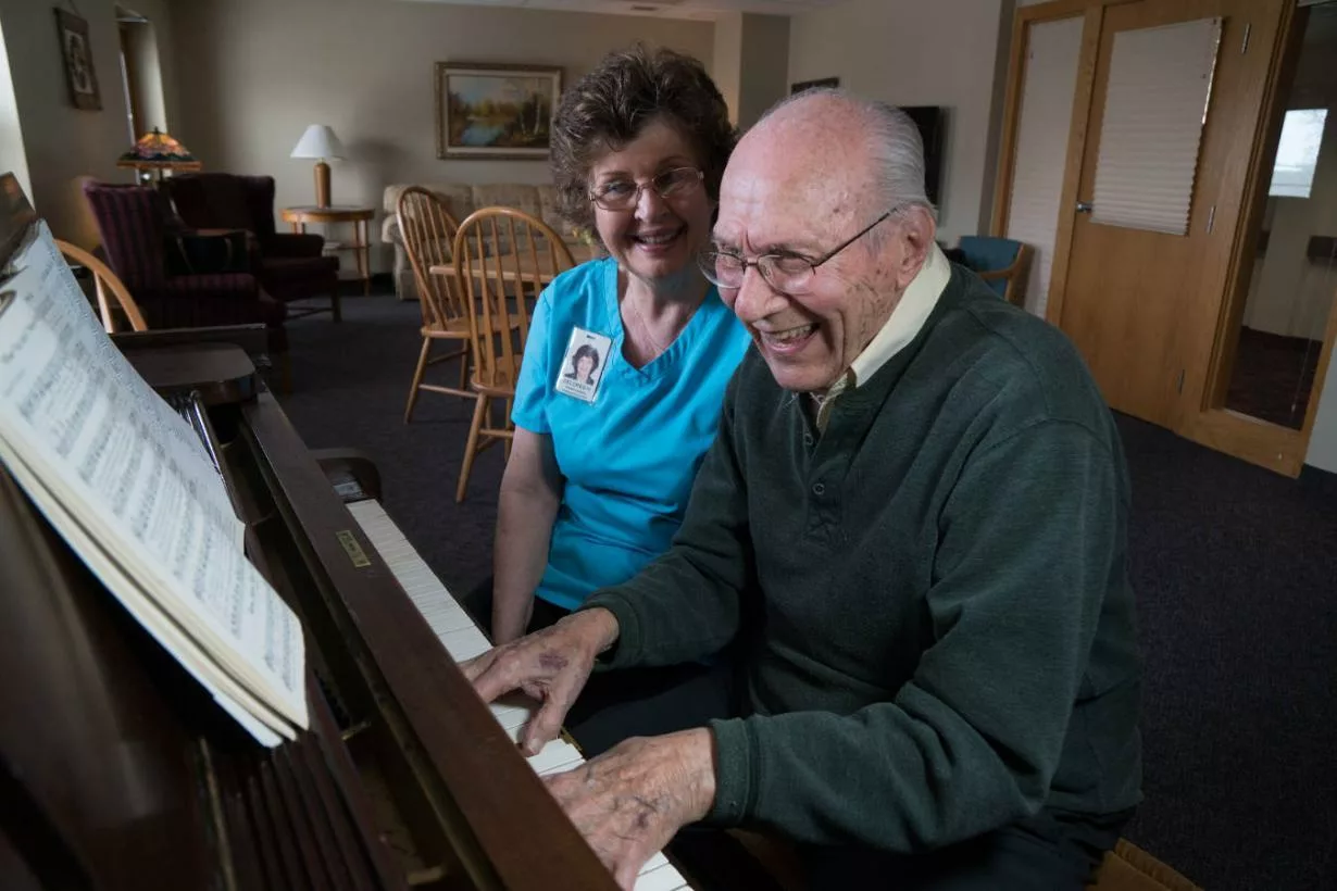 An elderly man enjoys playing a piano